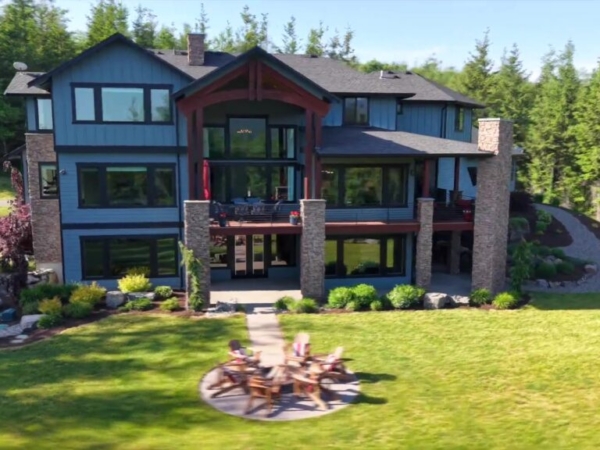 This view is hard to beat- showcasing the grand presence of the three-story custom home beautifully illuminated at night, with a private fire pit thoughtfully designed for evenings under the stars.